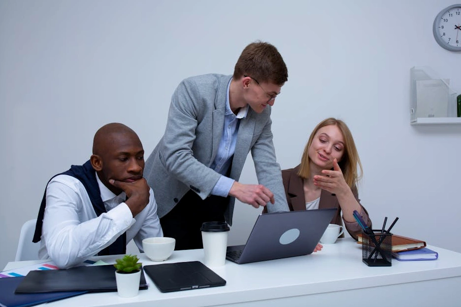 A diverse team of logistics professionals collaborating around a table with blueprints and a laptop.